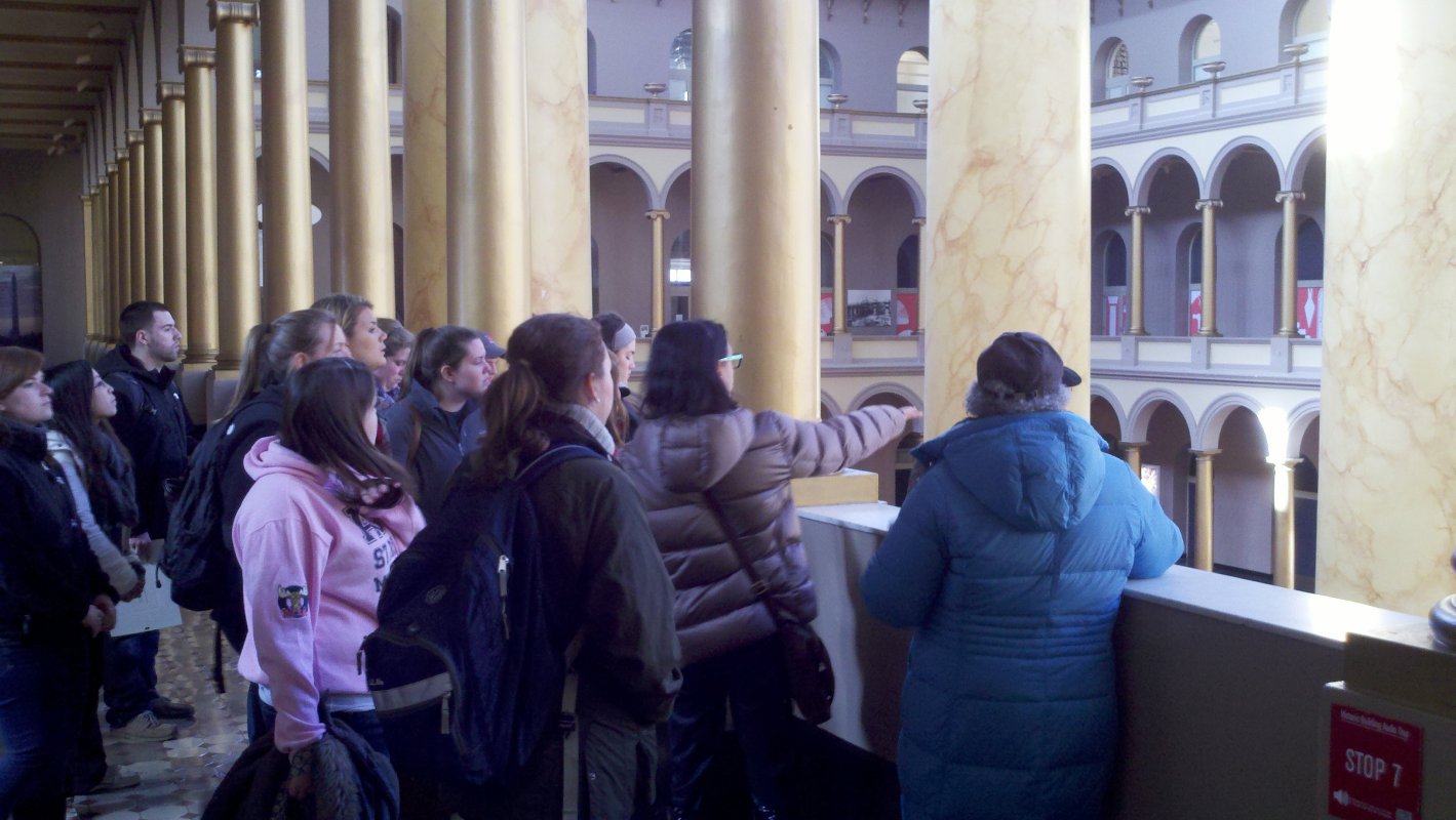 A tour guide discusses neo-classical architecture at the National Building Museum with Dr. Daughtery and students.